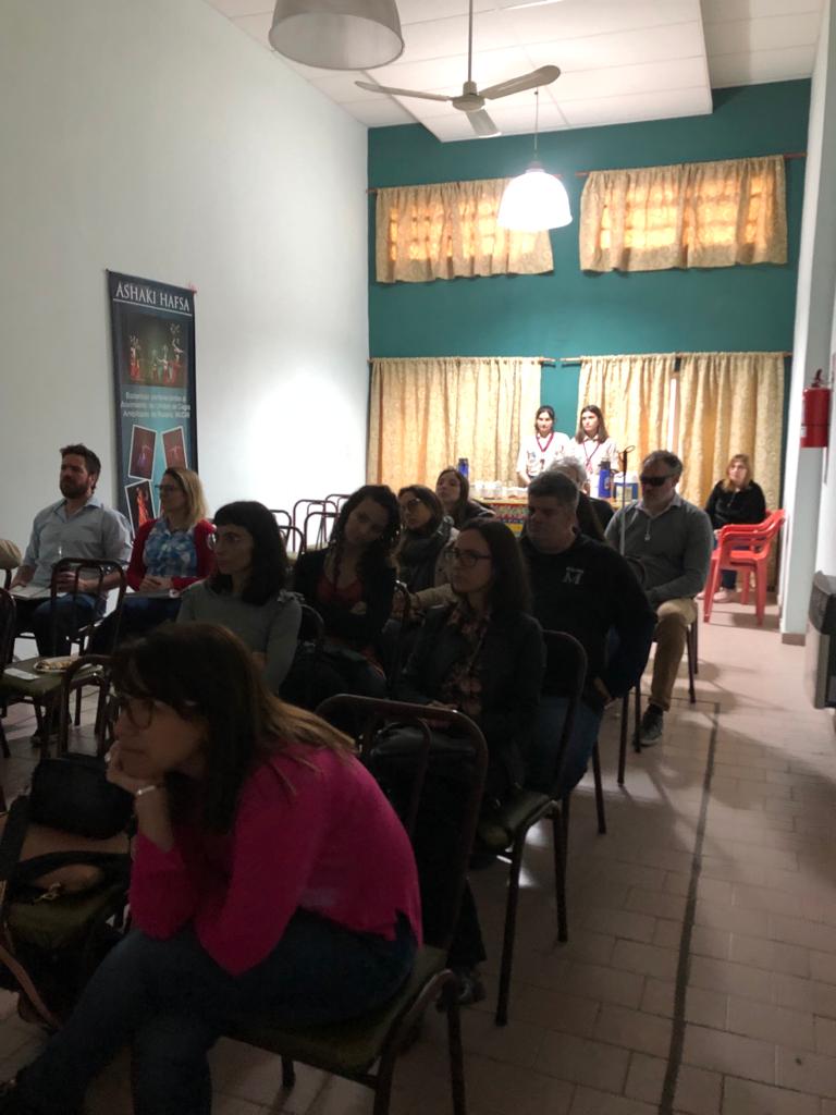Se ven alrededor de doce personas de diferentes empresas escuchando y mirando atentamente un video de la presentación del Programa Ágora en Rosario, en el edificio de MUCAR
